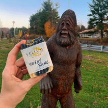 Load image into Gallery viewer, Hand holding a Yellun Honey Basil product in front of a wooden statue of Bigfoot outdoors.
